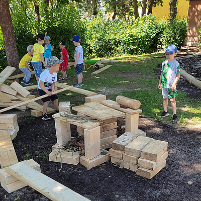 Kinder spielen im Garten der Erlöserkita Amberg mit großen Holzbausteinen
