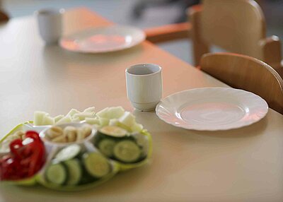 Ein gedeckter Esstisch aus dem evangelisch lutherischen Kindergarten in Tirschenreuth auf dem ein Teller mit viel Gemüse steht.