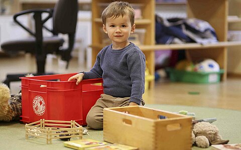 Ein kleiner Junge aus dem Kinderhaus Kunterbunt in Grafenwöhr, welcher mit Holzspielzeug spielt