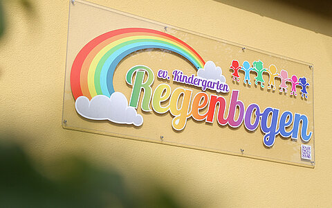 Das Logo des evangelischen Kindergarten Regenbogen in Erbendorf, welches an der Außenfassade hängt