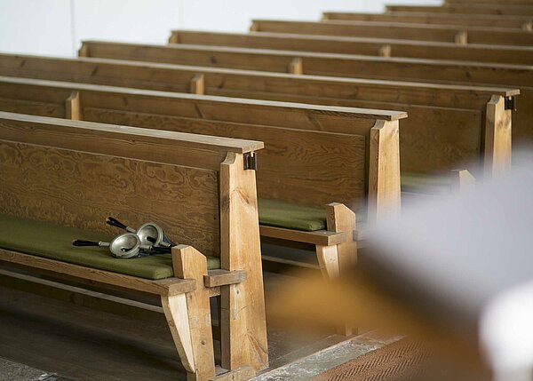 Bild: Die Sitzbänke in der Auferstehungskirche in Wiesau. Auf der vorderen Bank auf der linken Seite liegt eine rundliche Brille.
