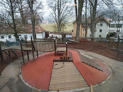 Spielbereich mit Holzsteg, Hangelnetz und Balancierwegen im Garten der Kita An der Allee