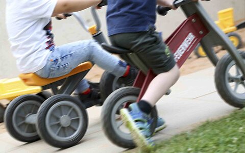 Zwei Kinder aus dem Haus für Kinder Gottfried Sperl in Vohenstrauß, welche auf Laufrädern durch die Gegend flitzen.