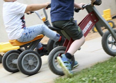 Zwei Kinder aus dem Haus für Kinder Gottfried Sperl in Vohenstrauß, welche auf Laufrädern durch die Gegend flitzen.