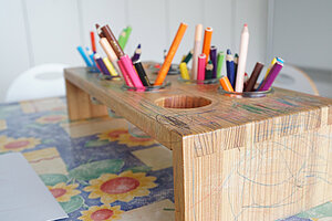 Buntstifte im Holzständer auf einem Maltisch
