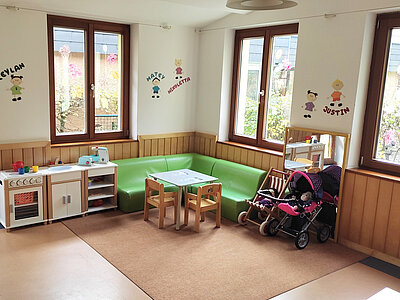 Spielecke mit Kinderküche, Puppenwagen und grüner Sitzecke in der Erlöserkita Amberg