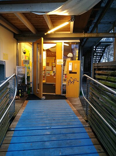 Eingang der Kita An der Allee in Sulzbach-Rosenberg mit gelber Tür und Infowand