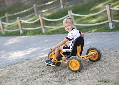 Ein Junge, der auf einem Dreirad-Rider im Garten der St. Michael Kita in Weiden fährt