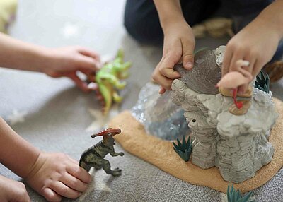 Zwei kleine Kinder aus dem evangelischen Kindergarten Regenbogen in Erbendorf, die mit Spielzeugdinosaurier spielen