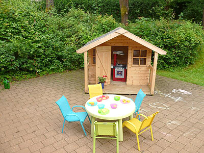 Spielhaus mit buntem Gartentisch und Stühlen auf der Terrasse der Kita Loderhof