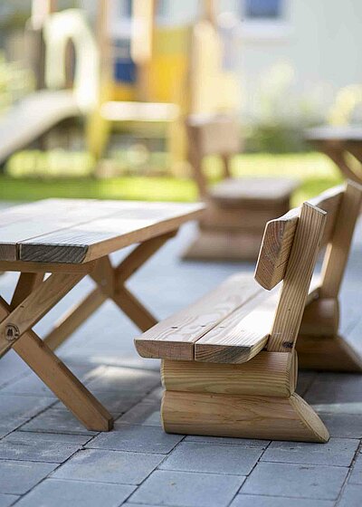 Sitzbänke aus Holz, welche im Garten der Kinderscheune Kreuz Christi in Weiden stehen.